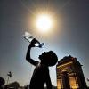 AI Generated-DALL·E- A child pouring water from a bottle into their mouth under the intense midday sun, with the backdrop of a famous New Delhi monument such as India Gate
